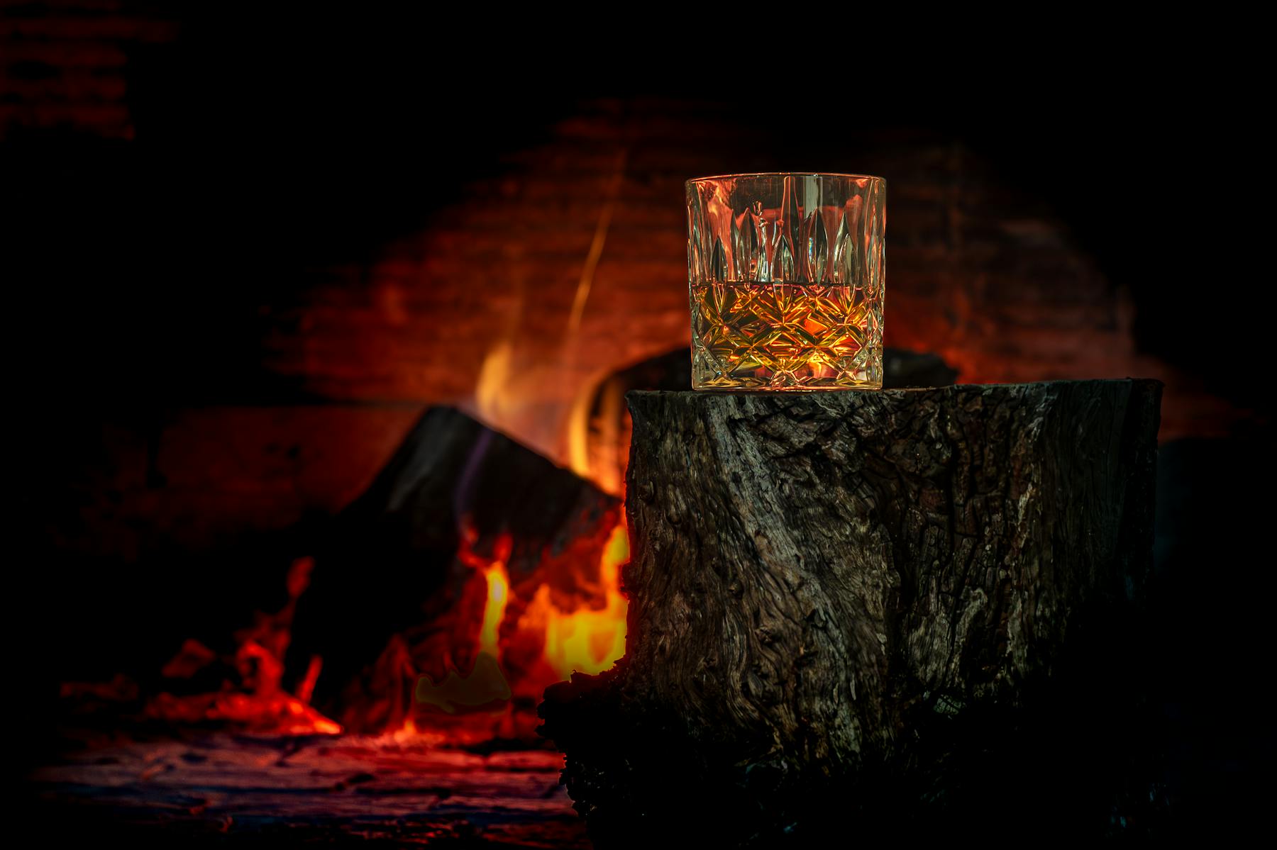 Whiskyglas foran en varm pejs